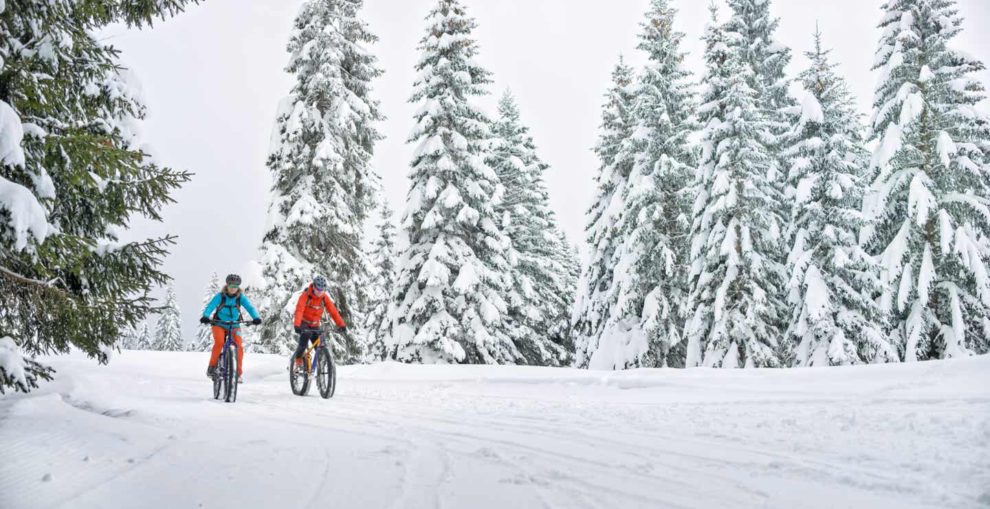 Pärchen radelt mit Fatbikes durch die winterliche Schneelandschaft