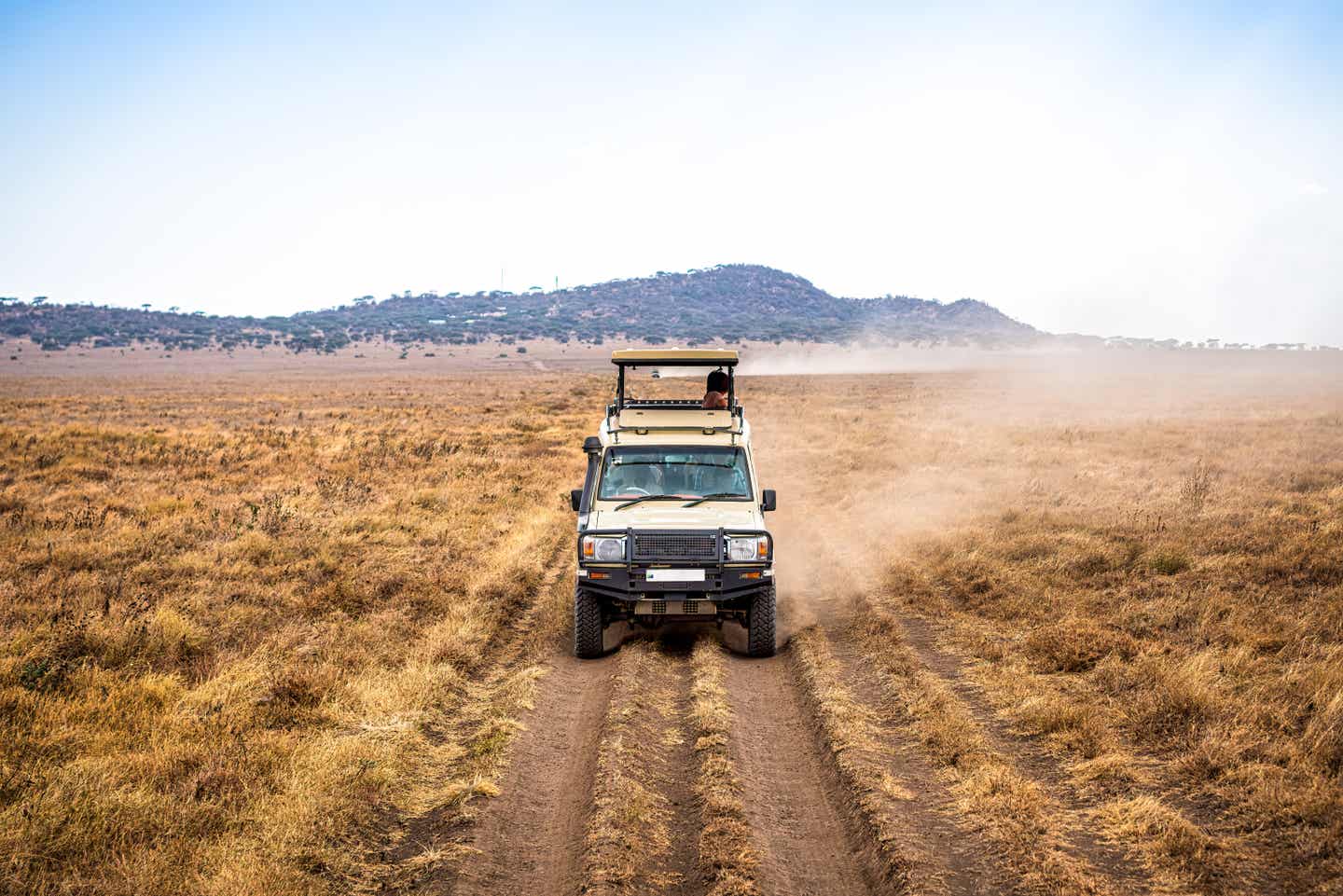 Safari-Wagen wirbelt Staub auf entlang einer Straße