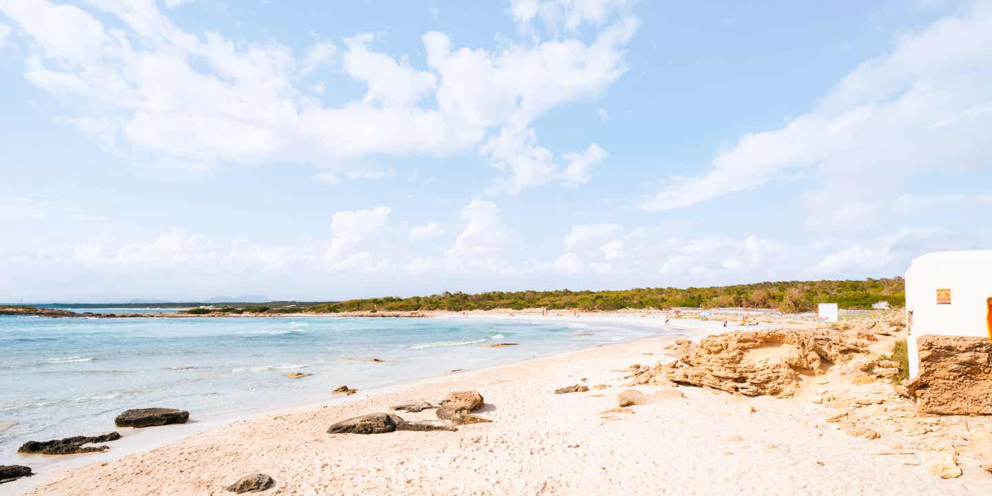 Blick auf einen Sandstrand mit Bucht und Landschaft im Hintergrund