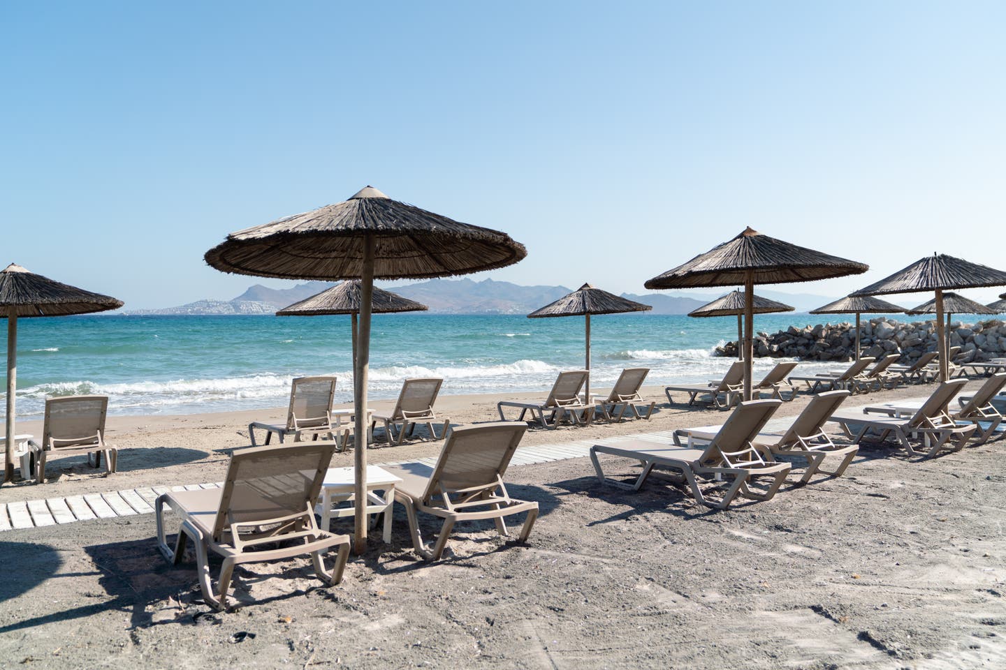 Sonnenschirme und Liegen am Strand mit Blick aufs Meer