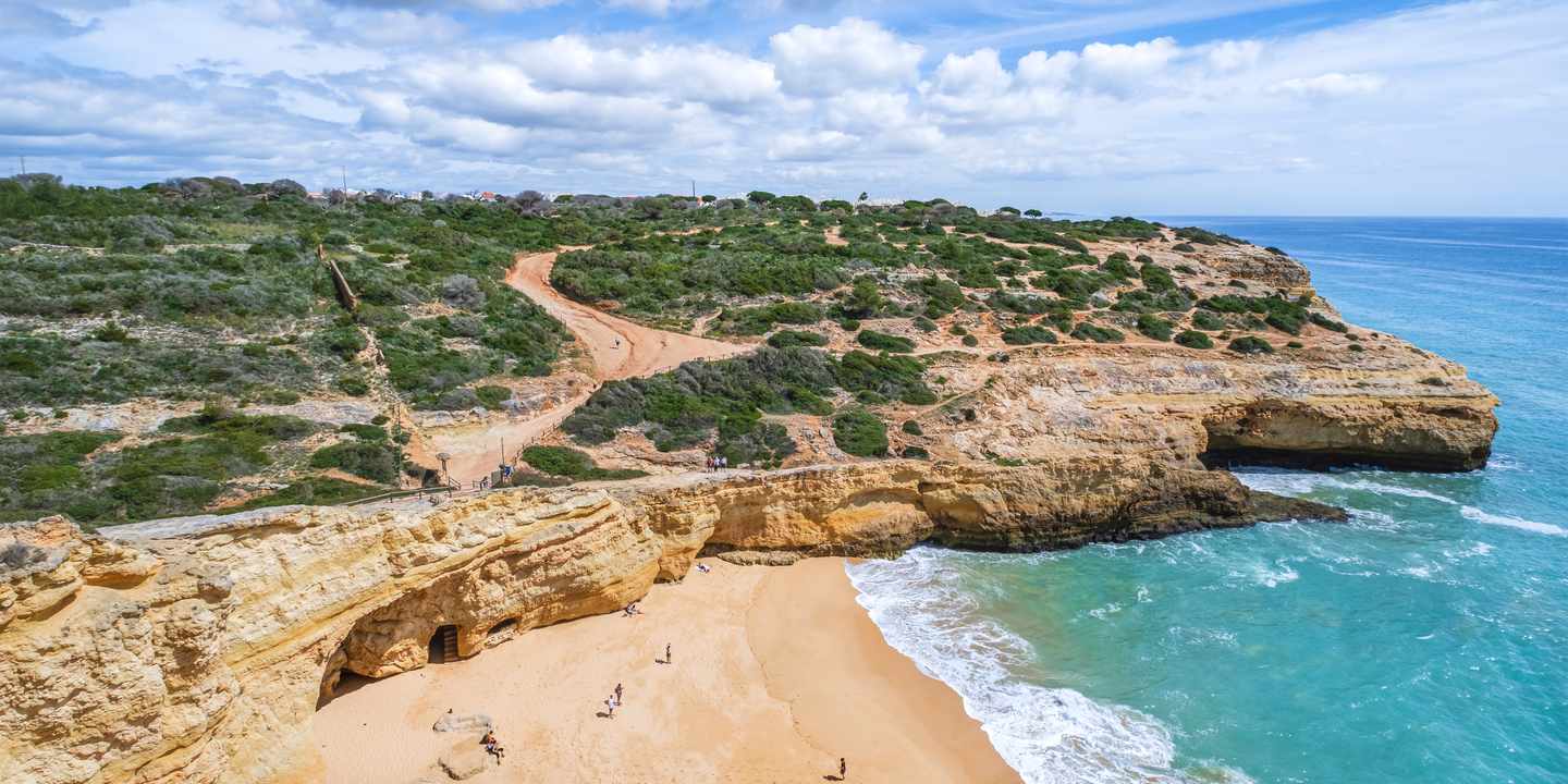 Praia do Carvalho an der Algarve mit heller Felsbucht, Sandstrand und türkisblauem Atlantik aus der Luft