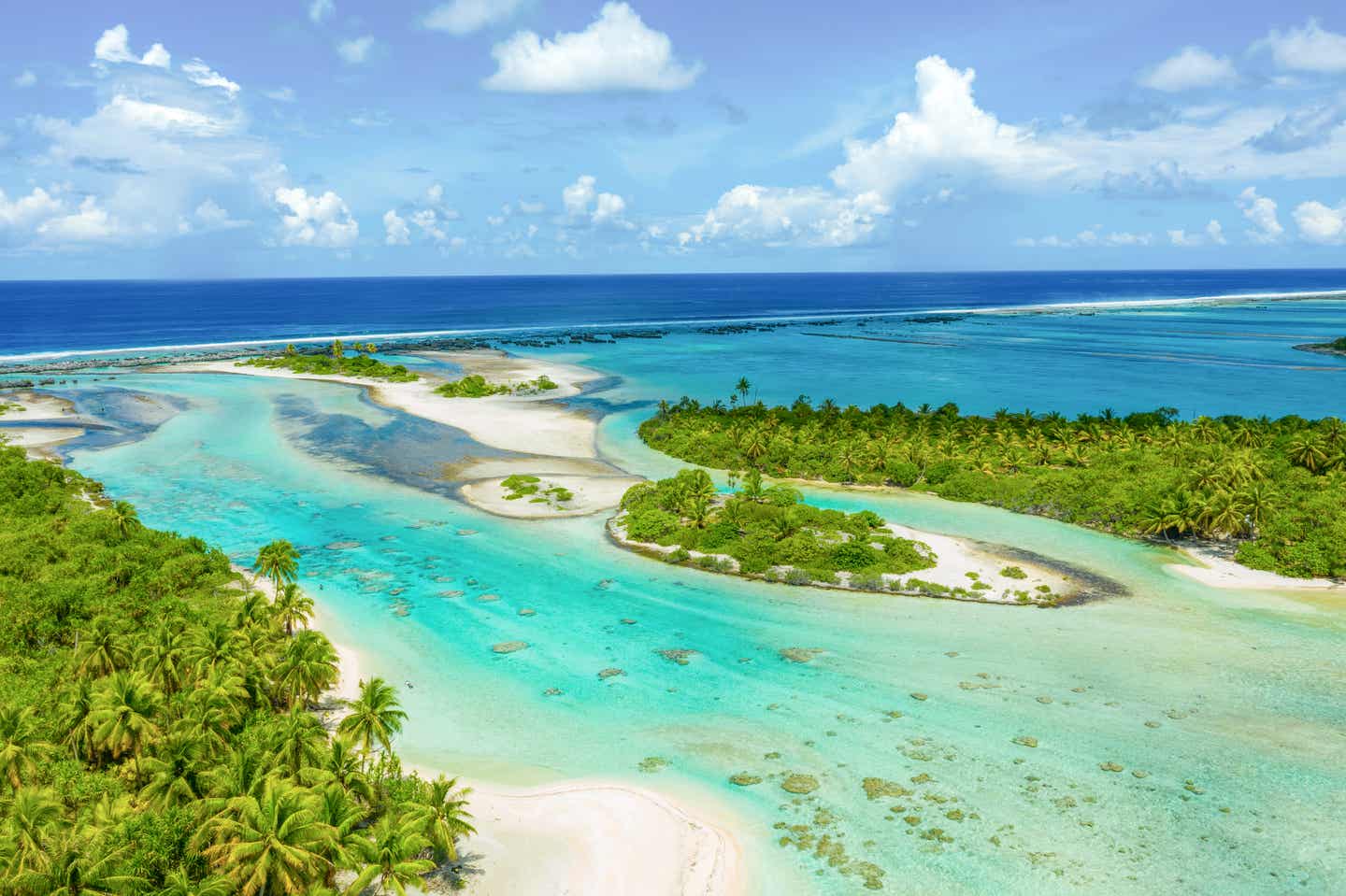 Rangiroa aus der Vogelperspektive, bewachsene Inseln und türkisblaues Wasser