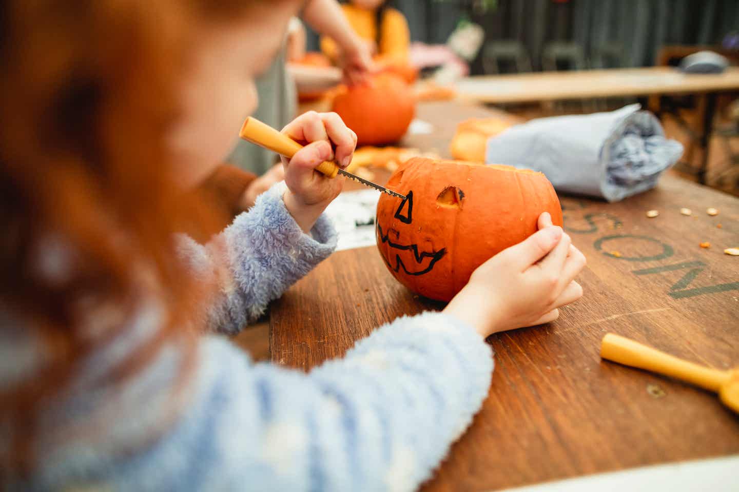 Reiseziele Oktober: Ein Kind schnitzt einen Kürbis für Halloween