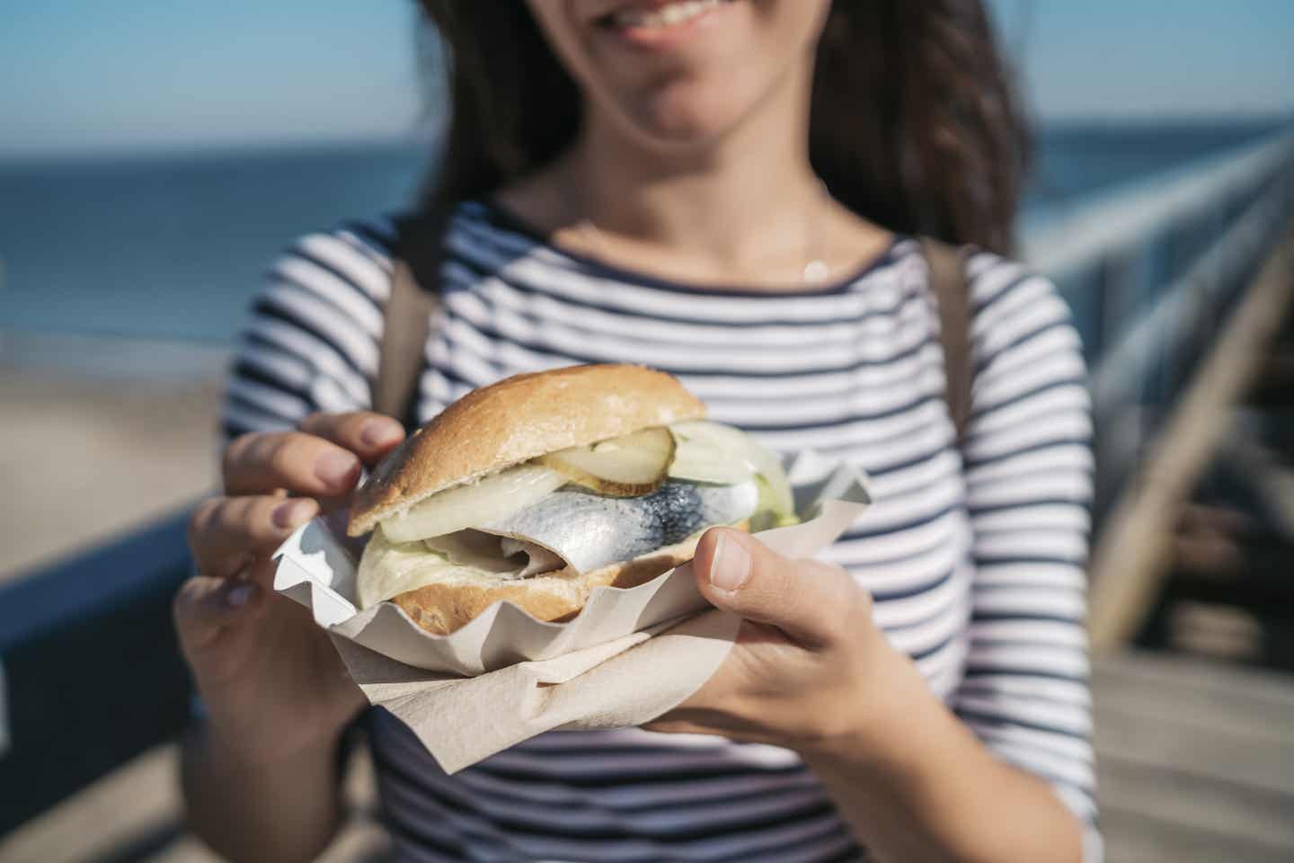 Travemünde Urlaub mit DERTOUR. Frau mit frischem Fischbrötchen in der Hand