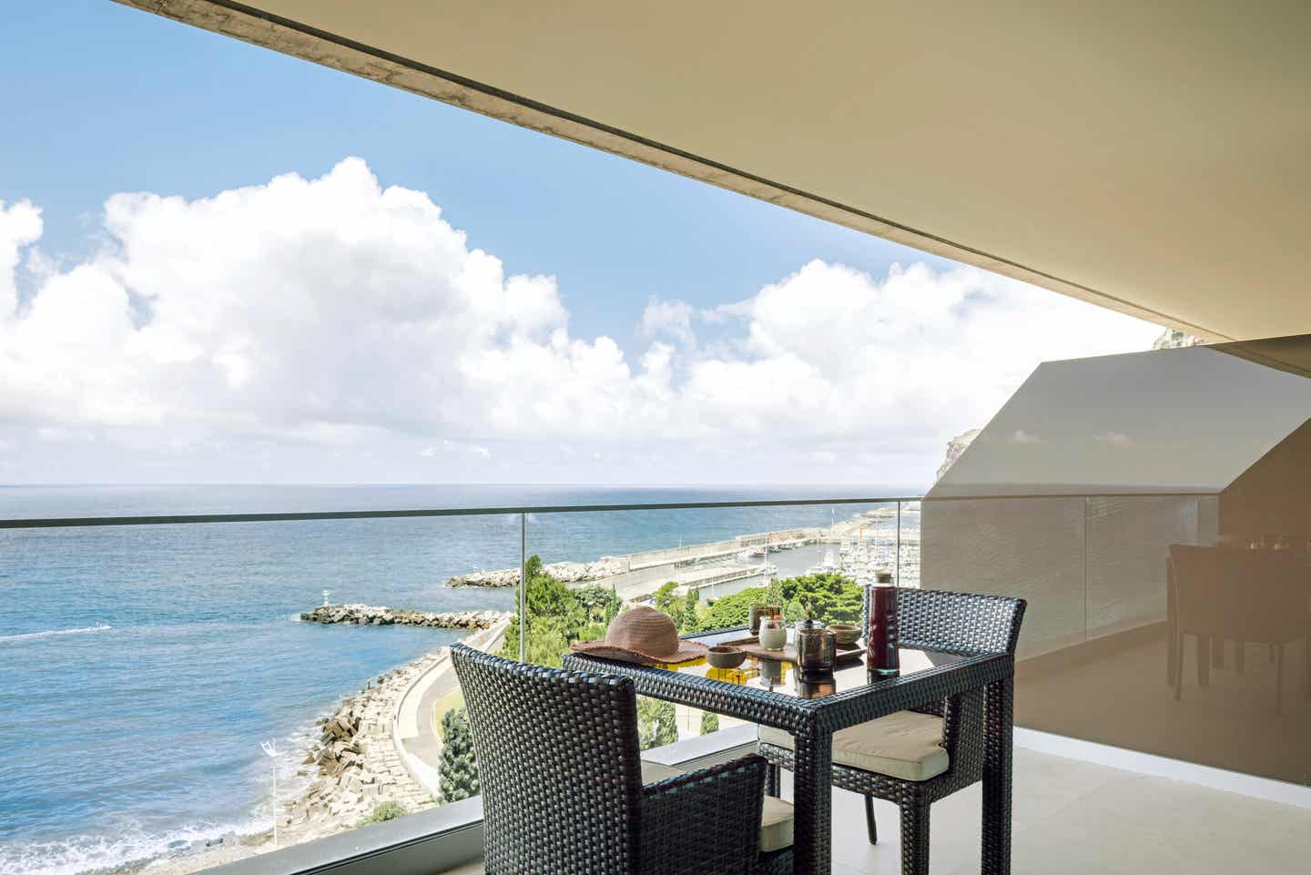 Gedeckter Tisch mit zwei Stühlen auf einem Balkon mit Blick auf die Bucht