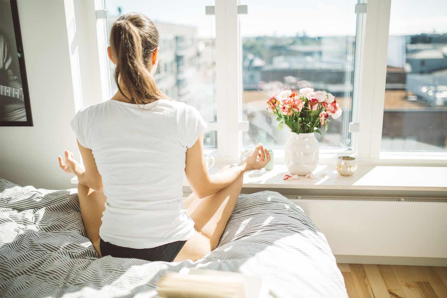 Deutschland Self Care Frau macht Yoga auf Bett