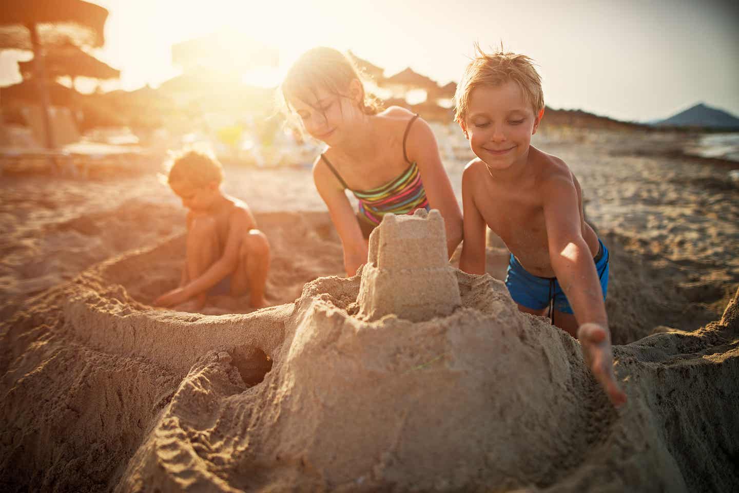 Kinder bauen eine Sandburg bei Sonnenuntergang