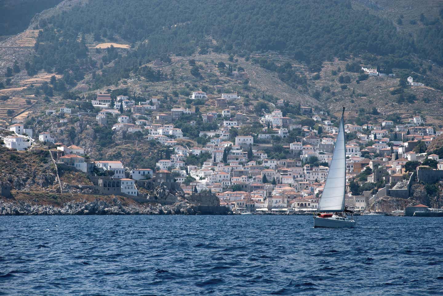 Paros Urlaub mit DERTOUR. Insel Paros vom Meer aus fotografiert mit Segelboot im Vordergrund