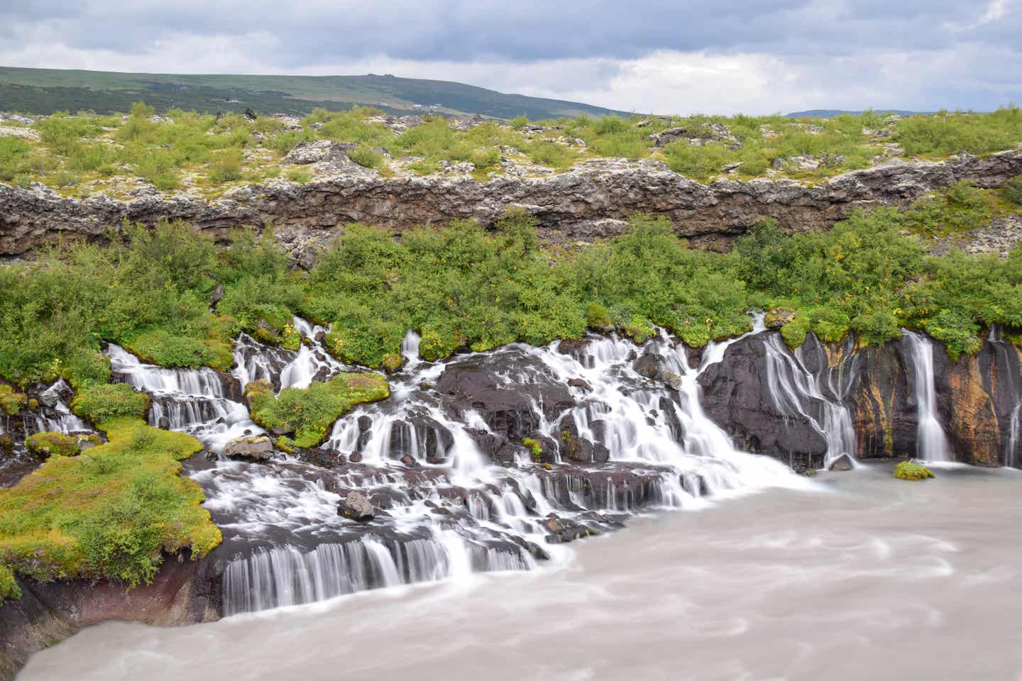 Wie ein Netz bahnt sich das Wasser des Hraunfossar-Wasserfallsystems auf Island seinen Weg über karge Felsen. 