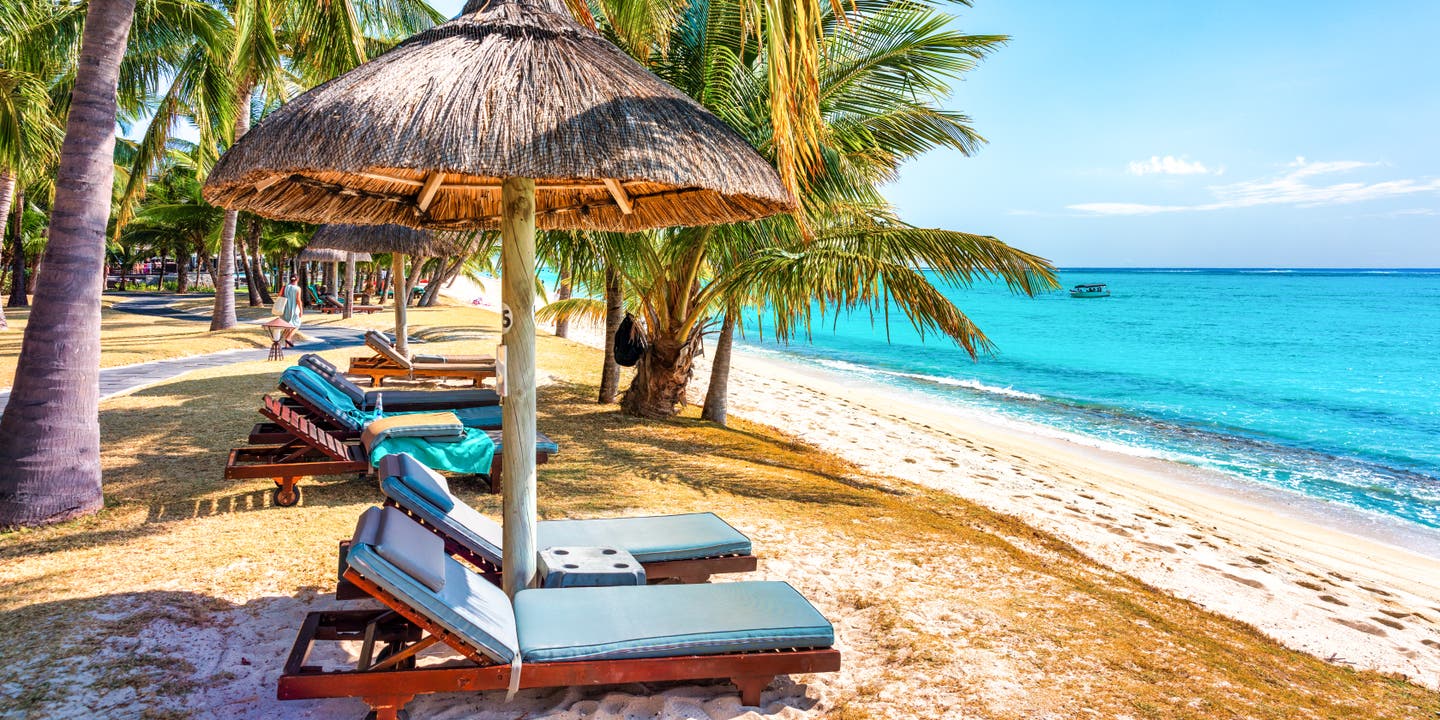 Strand von Le Morne Brabant auf Mauritius mit Palmen, Liegestühlen und türkisfarbenem Meer