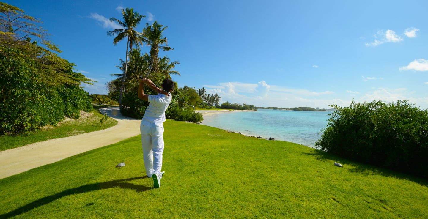 Mann schlägt einen Golfball ab