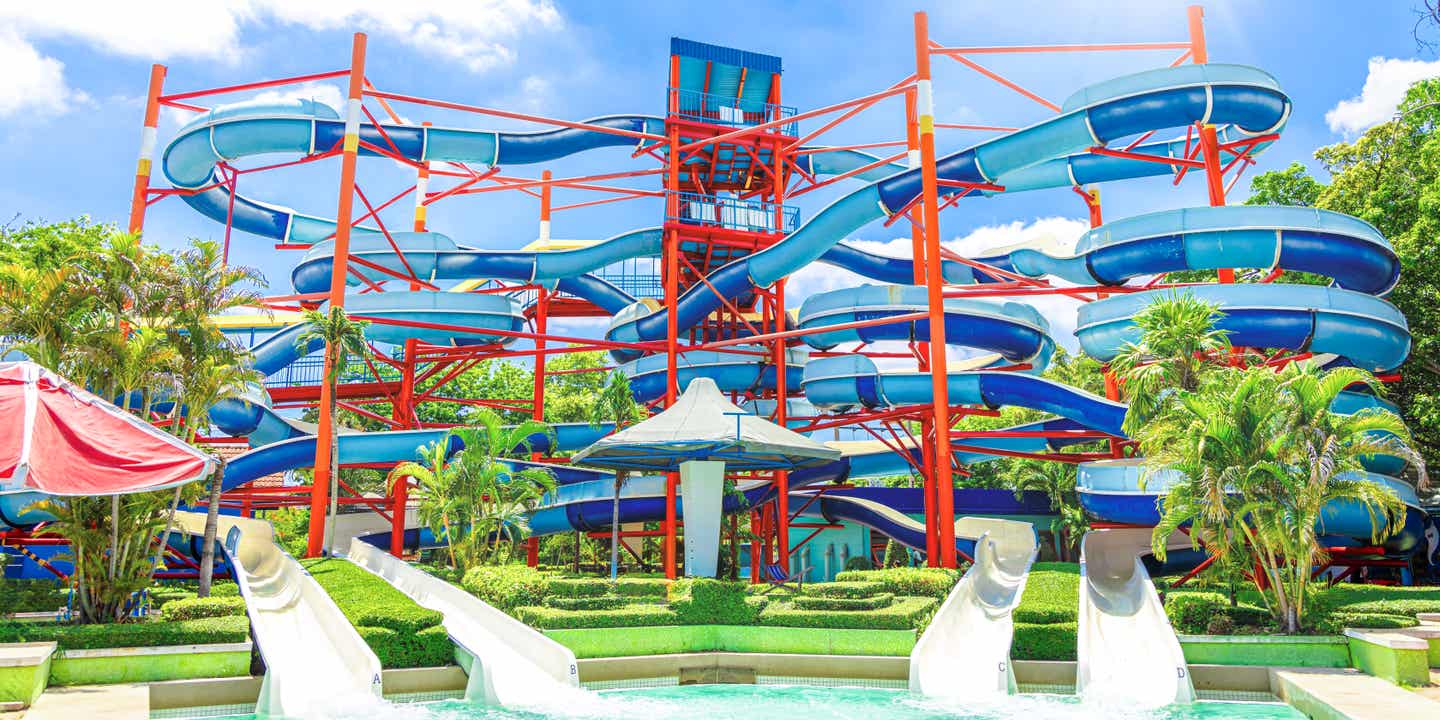 Geschwungene Wasserrutschen in Blautönen und einem roten Gerüst im Siam Park auf Teneriffa.