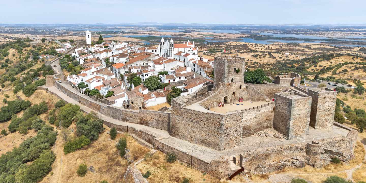 Luftaufnahme des mittelalterlichen Dorfes Monsaraz im Alentejo mit Burganlage und Blick auf den Alqueva-See