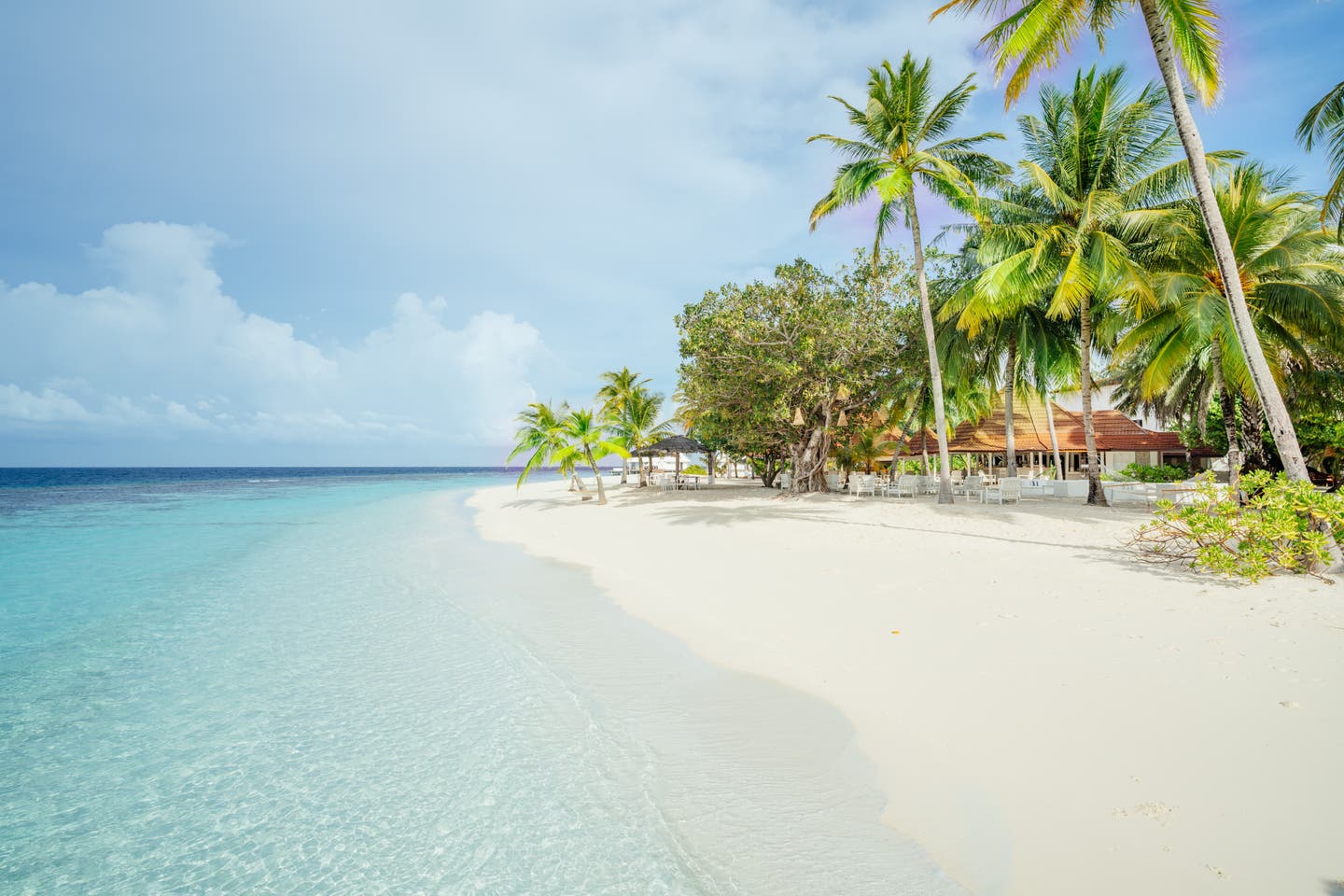 Blick entlang des weißen Hotelstrands unter Palmen