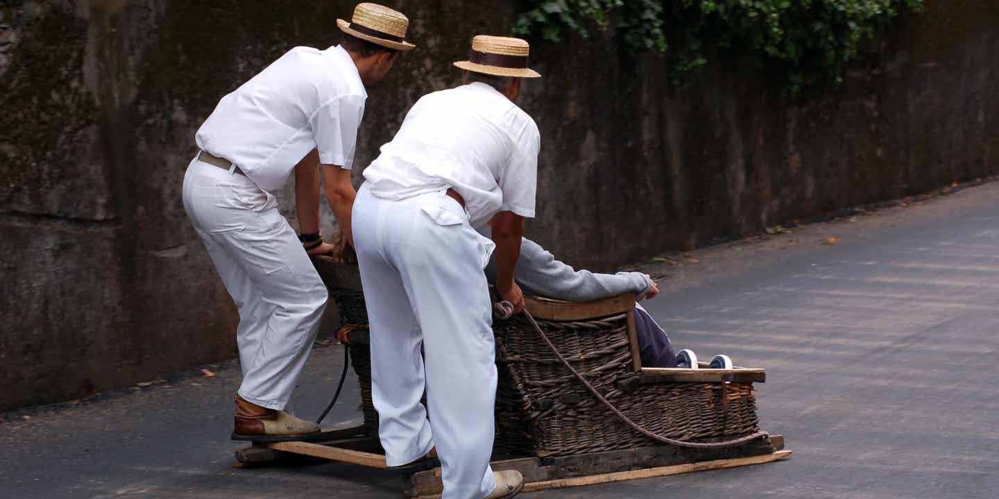 Korbschlitten auf Madeira mit klassisch weiß gekleideten Schlittenführern
