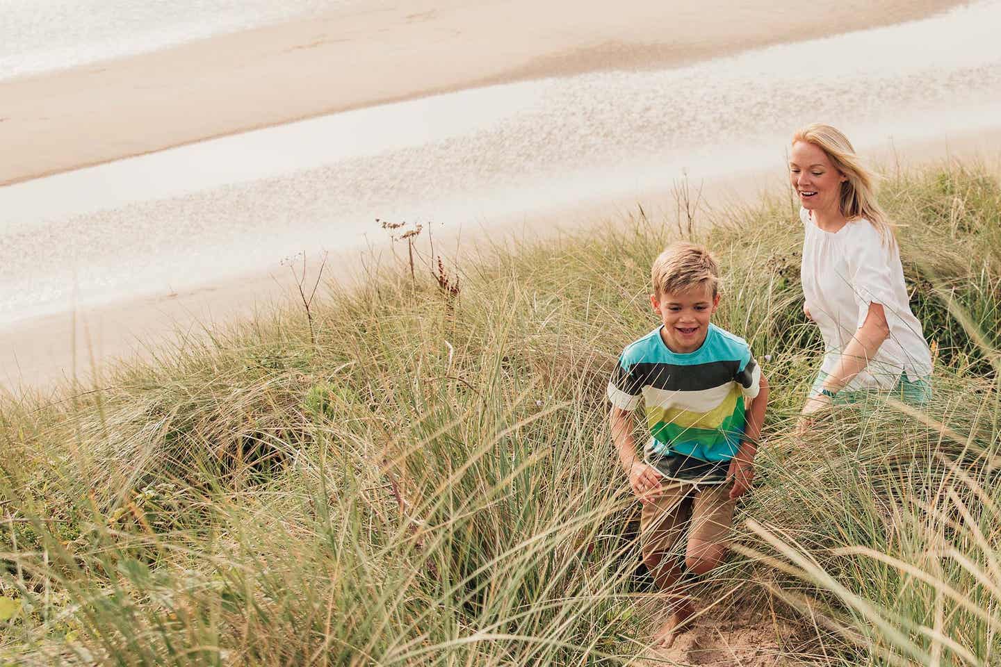 Eine Mutter wandert mit ihrem Sohn zwischen den Dünen im Urlaub an der Ostsee