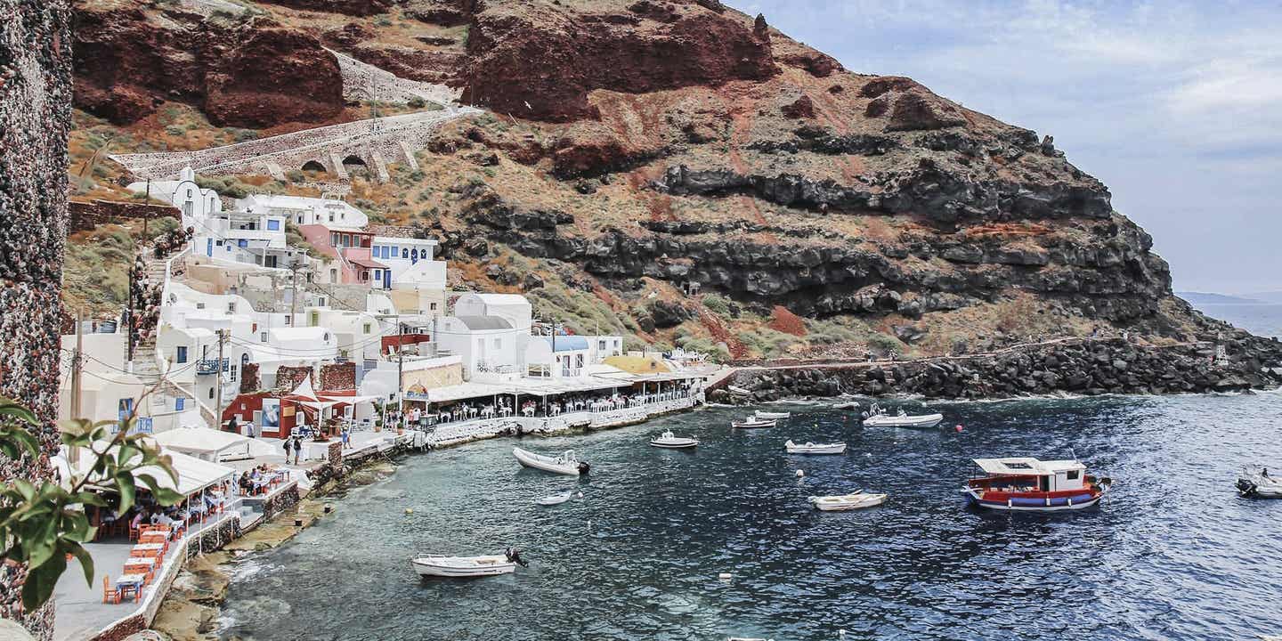 Santorinis Strände: Blick auf Hafen Amoudi Bay mit roten Klippen und weißen Häusern