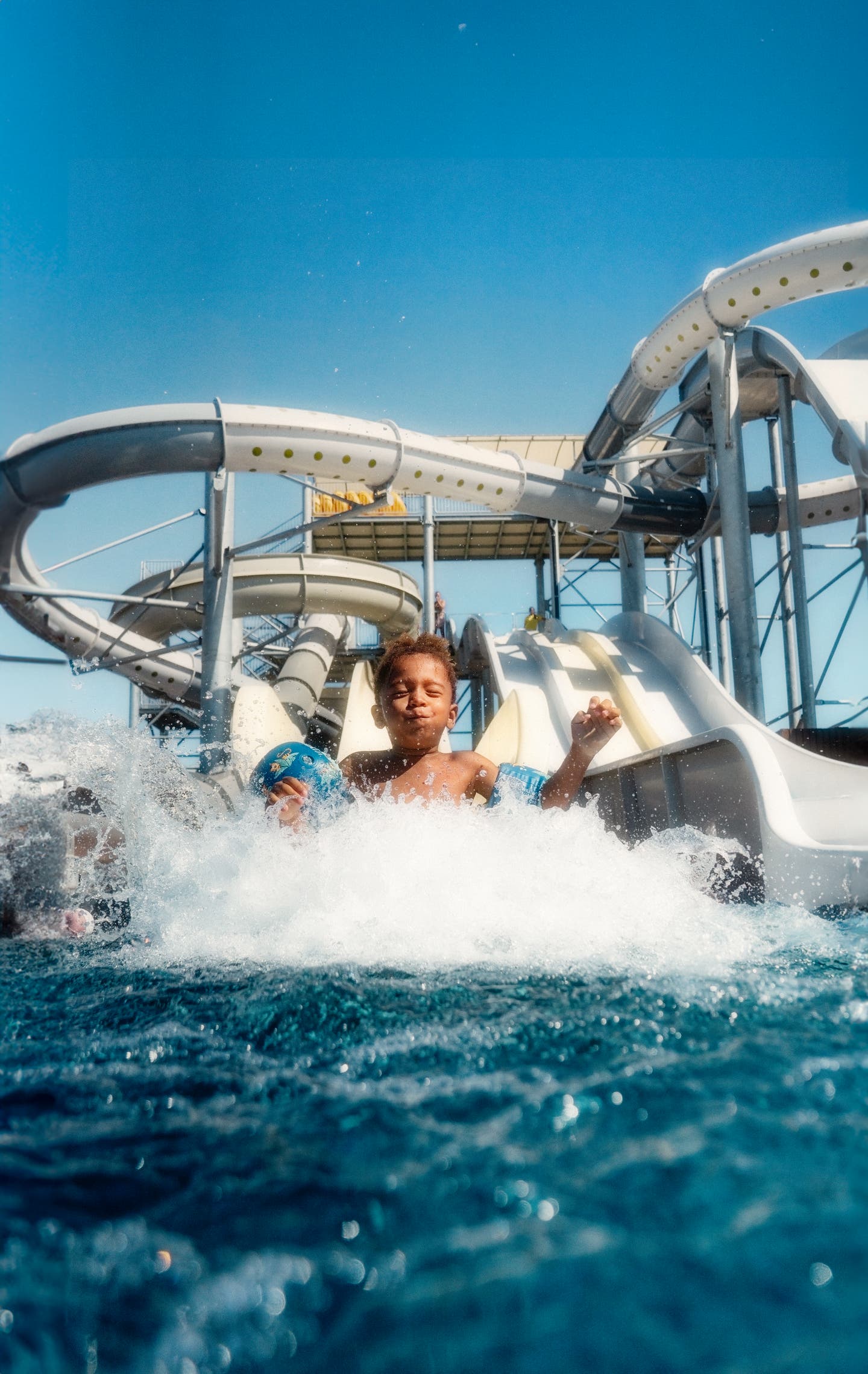 Ein Junge rutscht im Familienurlaub begeistert eine Wasserrutsche runter.