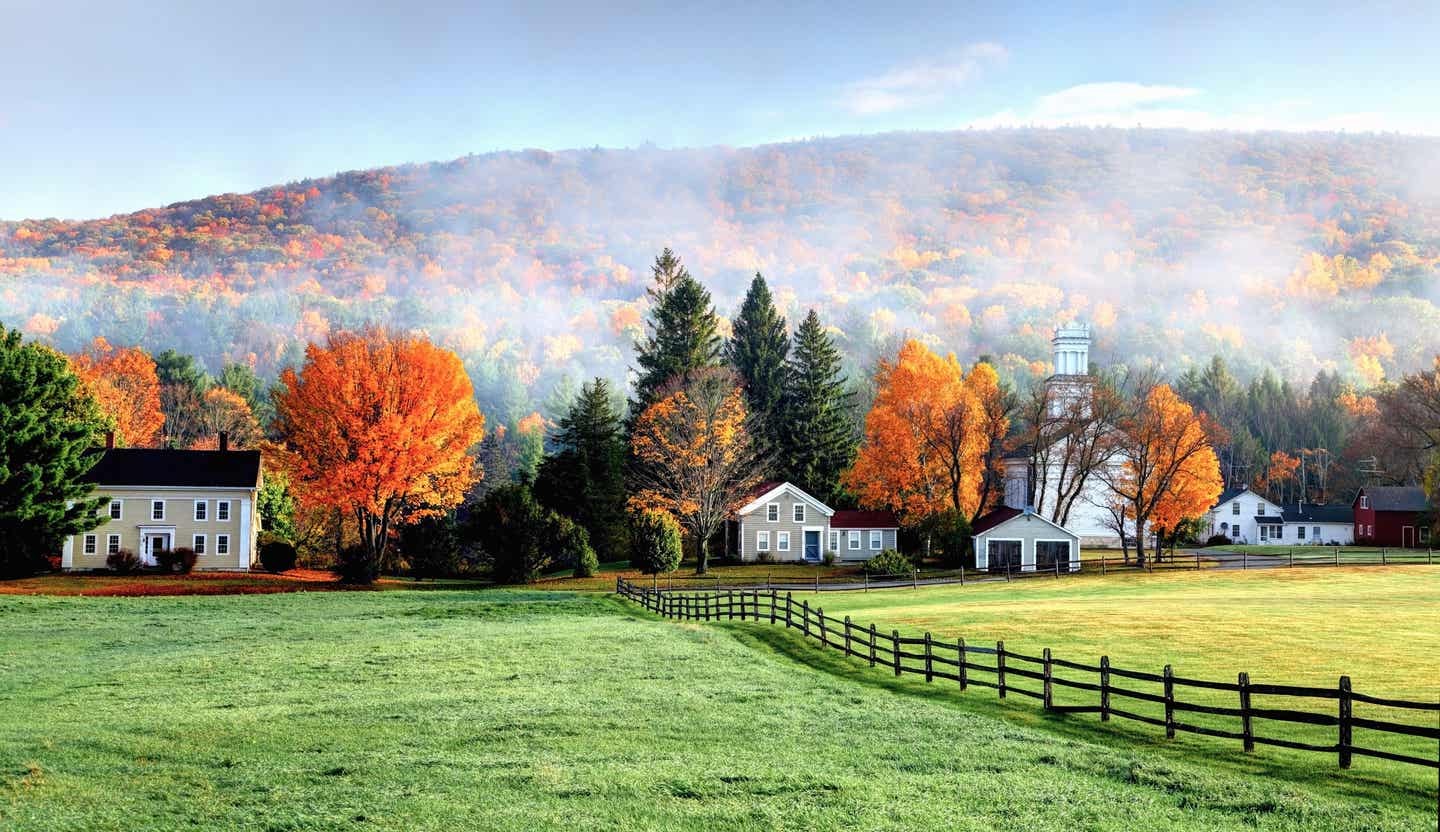 Blick auf bunte Bäume und Nebelschwaden mit kleinen Häusern in den USA
