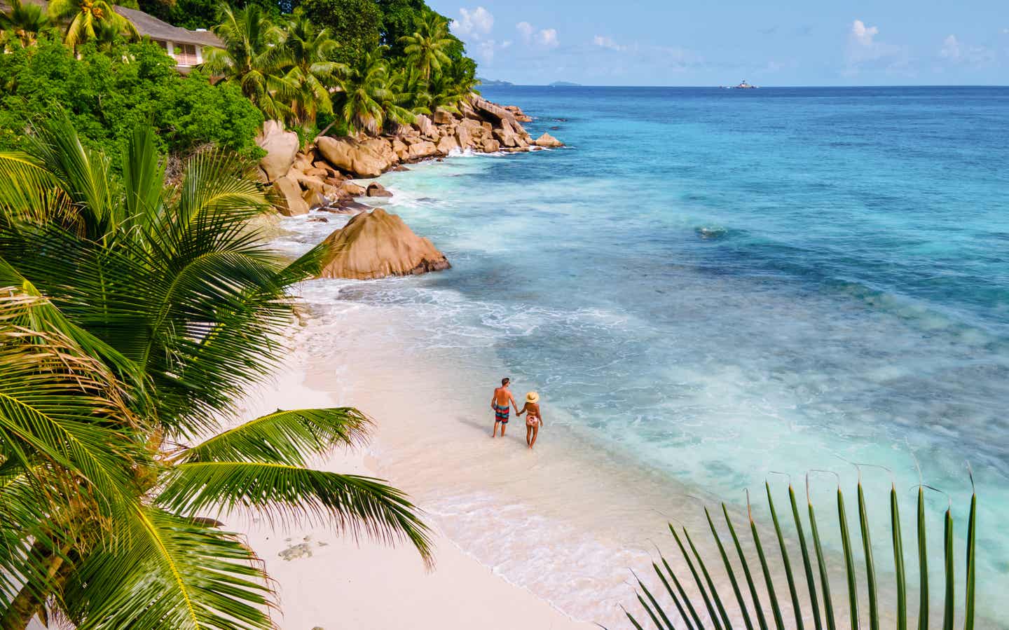 Paar im Seychellen-Urlaub aus der Vogelperspektive am Strand mit Palmen