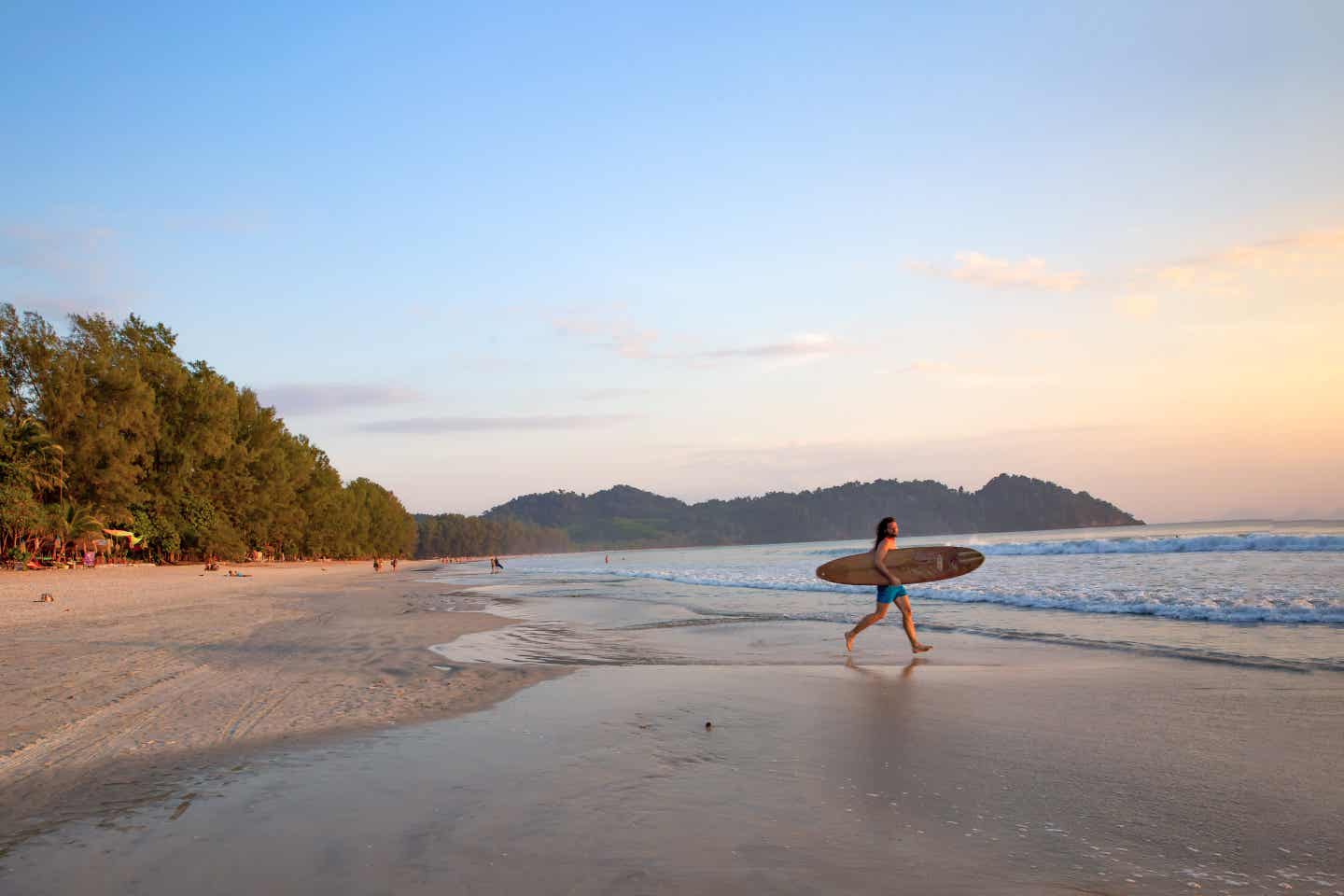 Schönste Strände Thailands: Surfer läuft dem Sonnenuntergang entgegen