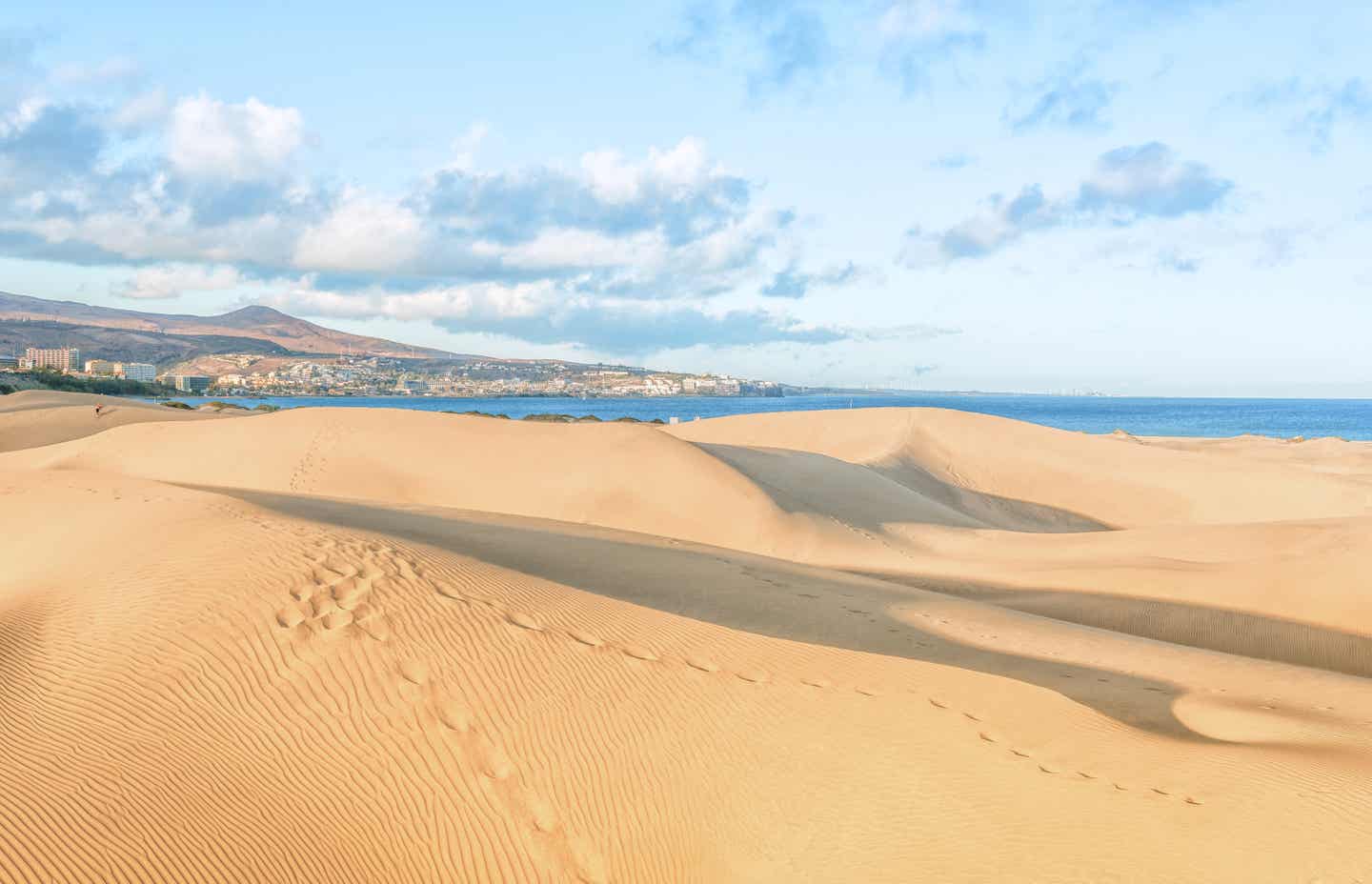 Sanddünen von Maspalomas mit dahinterliegender Stadt und Meer, Fußspuren im Sand