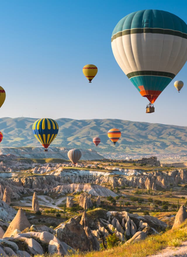 Rundreisen Türkei Rundreisen Türkei: Heißluftballons im Himmel über der Felsenlandschaft Kappadokiens