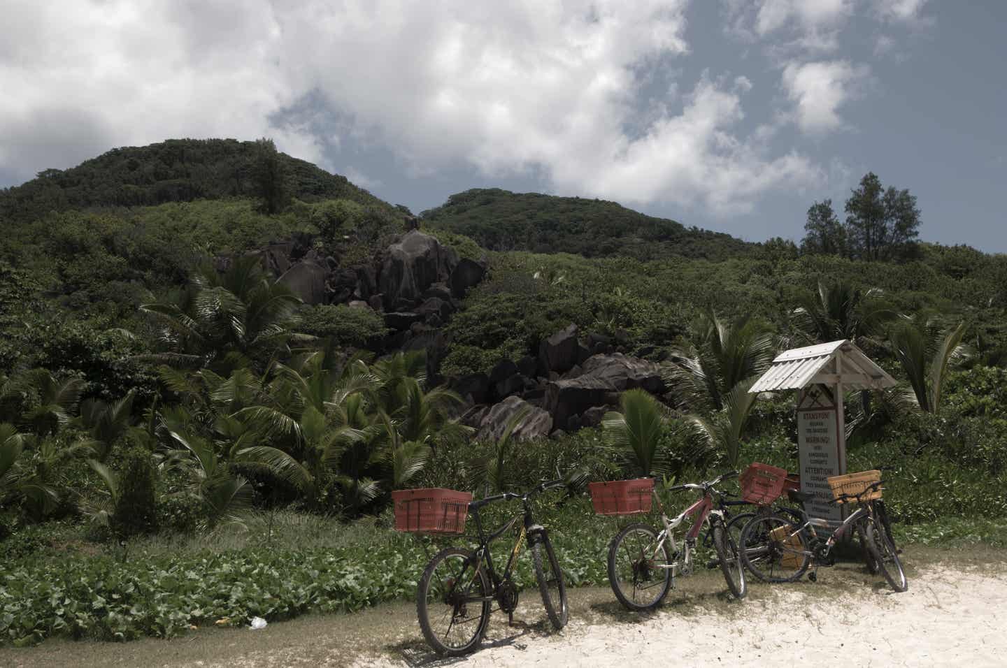 Grenada Urlaub mit DERTOUR. Eine Gruppe von Fahrrädern an einem Schild vor dem Grand-Anse-Strand, Grenada