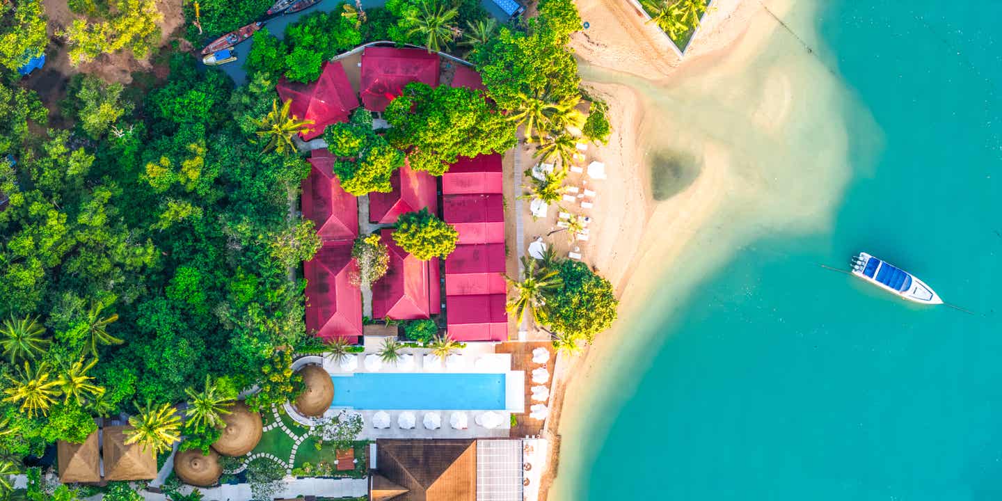 Luftaufnahme eines Resorts am Bo Phut Beach, einem der Koh Samui Strände mit Infinitypool, Liegen und Boot am ruhigen Ufer