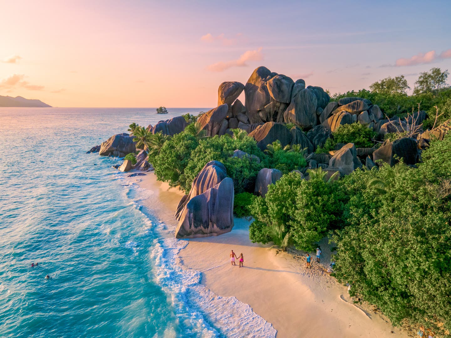Ein Paar genießt den goldenen Sonnenuntergang am berühmten Strand Anse Source d'Argent auf La Digue, Seychellen