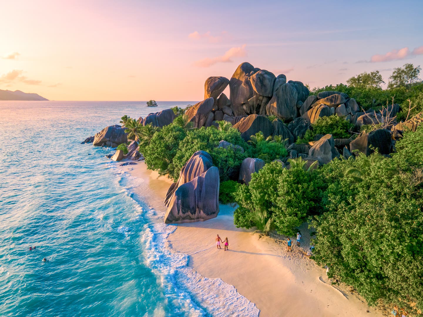 Ein Paar genießt den goldenen Sonnenuntergang am berühmten Strand Anse Source d'Argent auf La Digue, Seychellen