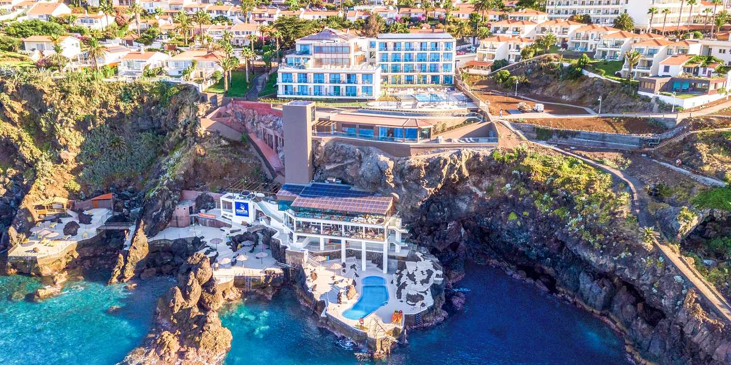 Außenansicht des Sentido Galomar auf Madeira mit Hotelgebäuden auf steilen Klippen über dem Atlantik und direktem Zugang zum Meer
