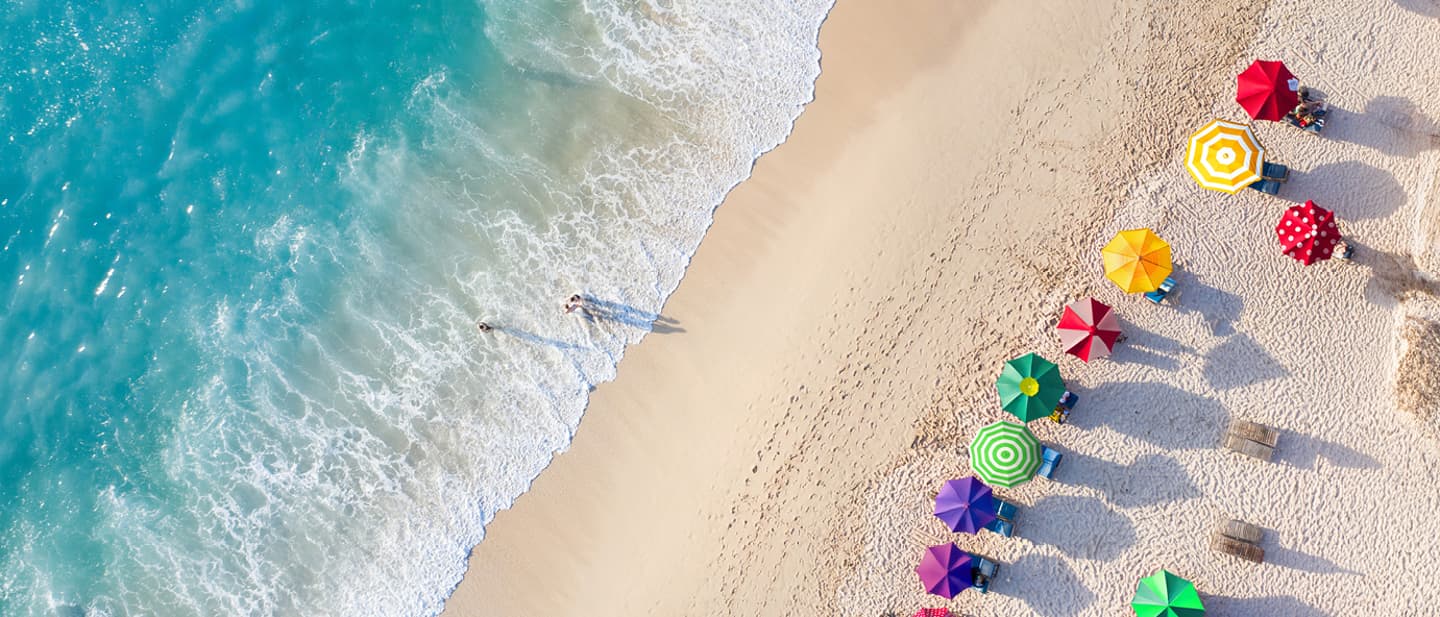 DEALS: Strand von oben mit bunten Sonnenschirmen