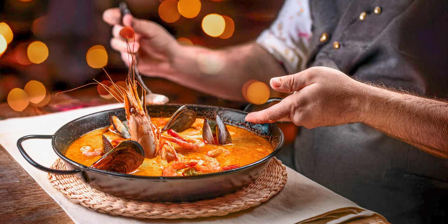 Ein Koch bereitet ein menorquinisches Gericht mit Langusten zu