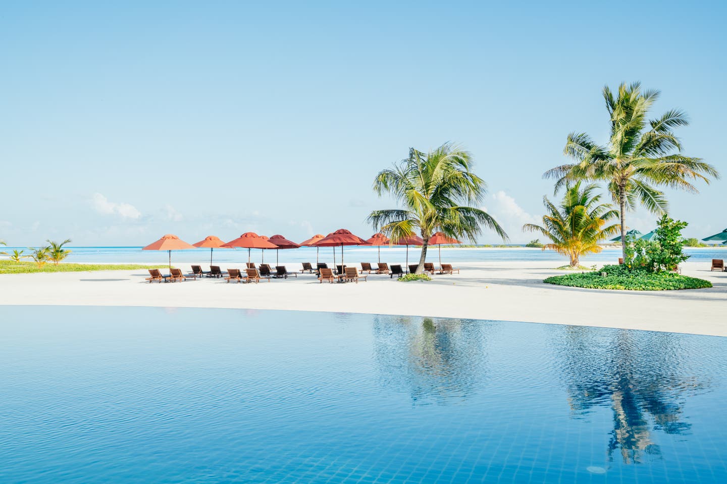 Poolanlage und Sonnenliegen direkt neben dem Strand