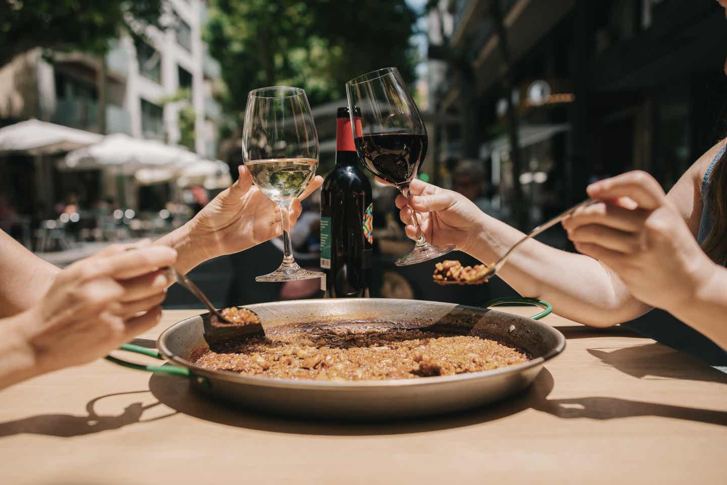 Playa de Muro Urlaub mit DERTOUR. Paar isst Paella und trinkt Wein dazu