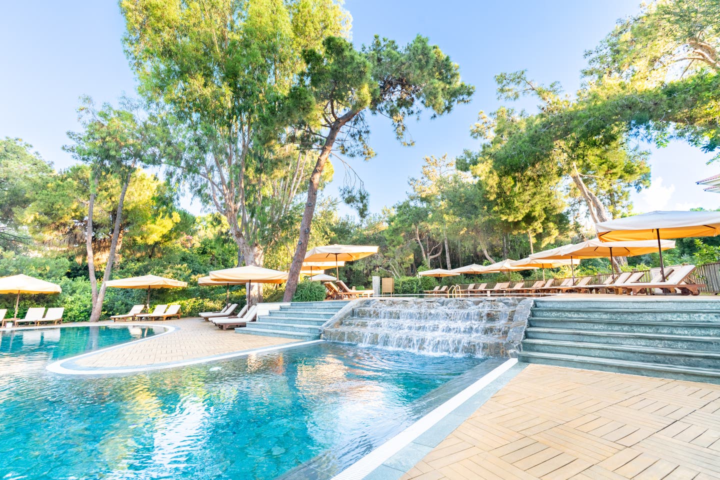 Pool mit kleinem Wasserfall und Sonnenliegen