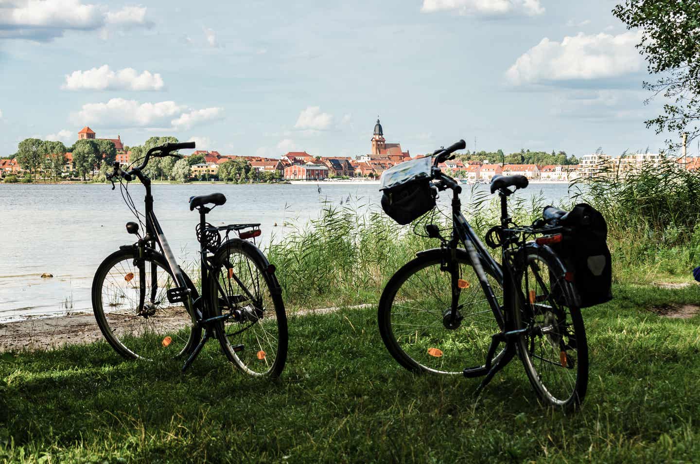 Meckenburgische Seenplatte Urlaub mit DERTOUR. Zwei abgestellte Fahrräder an der Müritz mit Waren an der Müritz im Hintergrund