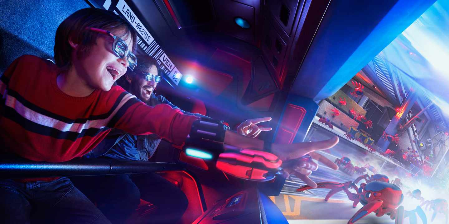 Ein Junge und ein Mann im Spinnen-SImulator auf dem Marvel Avengers Campus