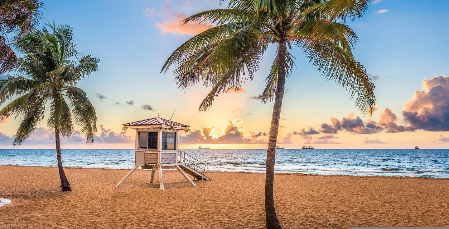 Ein Rettungsschwimmerturm an einem Strand in Florida mit Palmen im Sonnenunterrgang