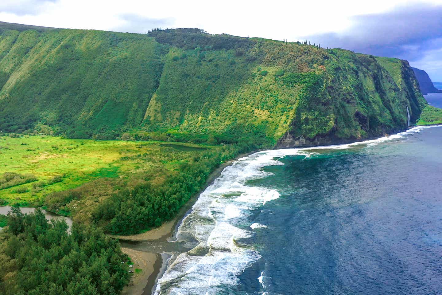 Grüne Bergformationen und schwarzer Lavastrand auf Big Island, Hawaii