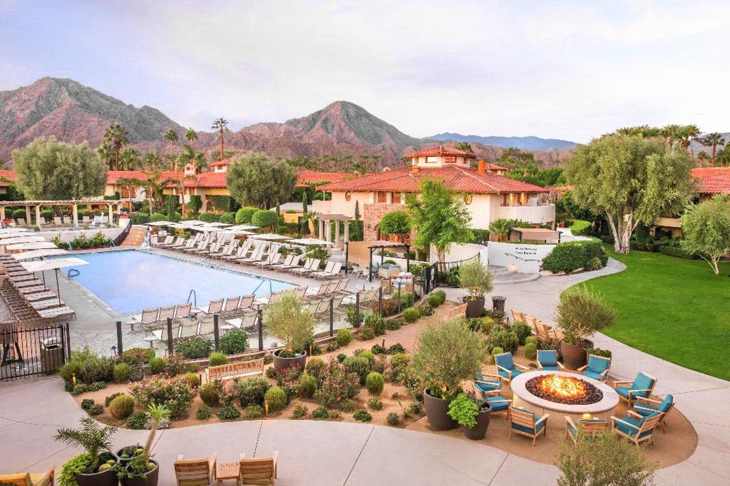 Blick auf das Coachella-Hotel Miramonte Resort & Spa in Kalifornien mit Pool, Feuerstelle und einem Bergpanorama im Hintergrund