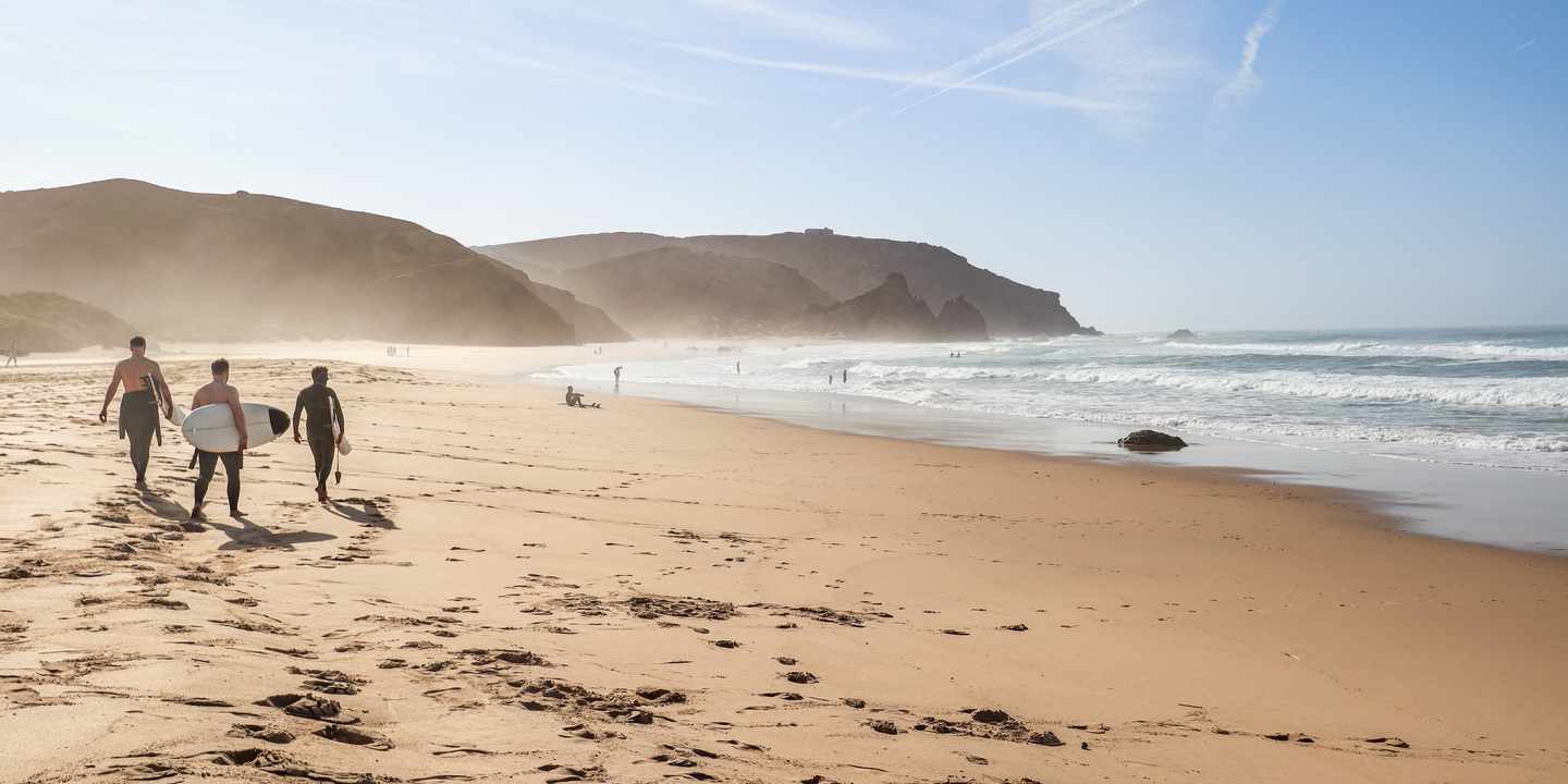 Praia do Amado an der Costa Vicentina mit breitem Sandstrand, Atlantikwellen und Surfern am Ufer