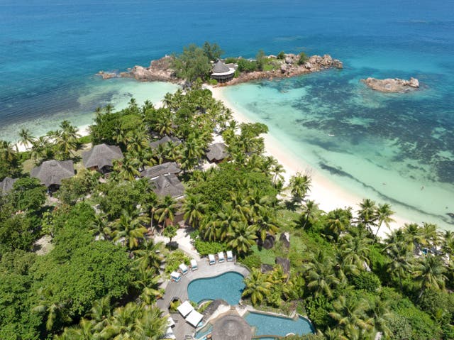 Luftbild einer Außenansicht des Hotels mit Unterkünften und Pool zwischen Palmen direkt am Strand
