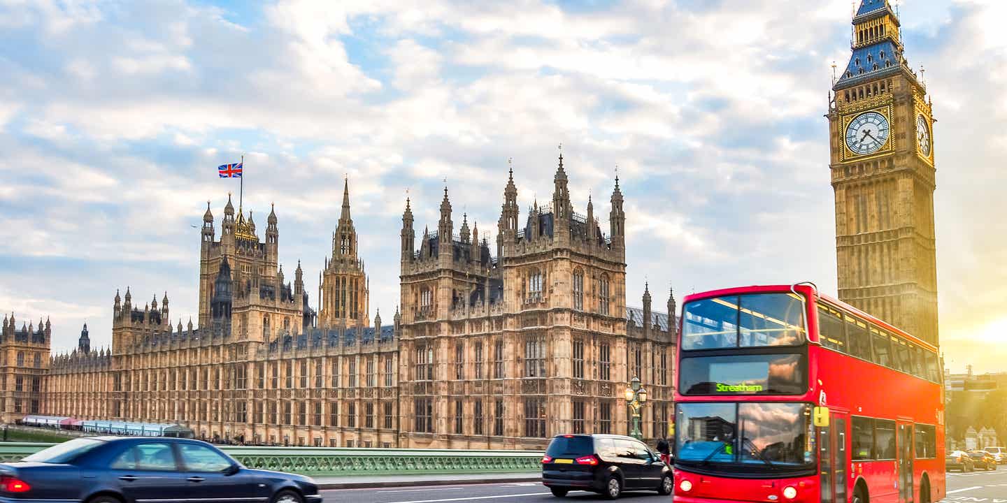 Big Ben und Houses of Parliament in London mit rotem Doppeldeckerbus bei Sonnenuntergang auf der Westminster Bridge