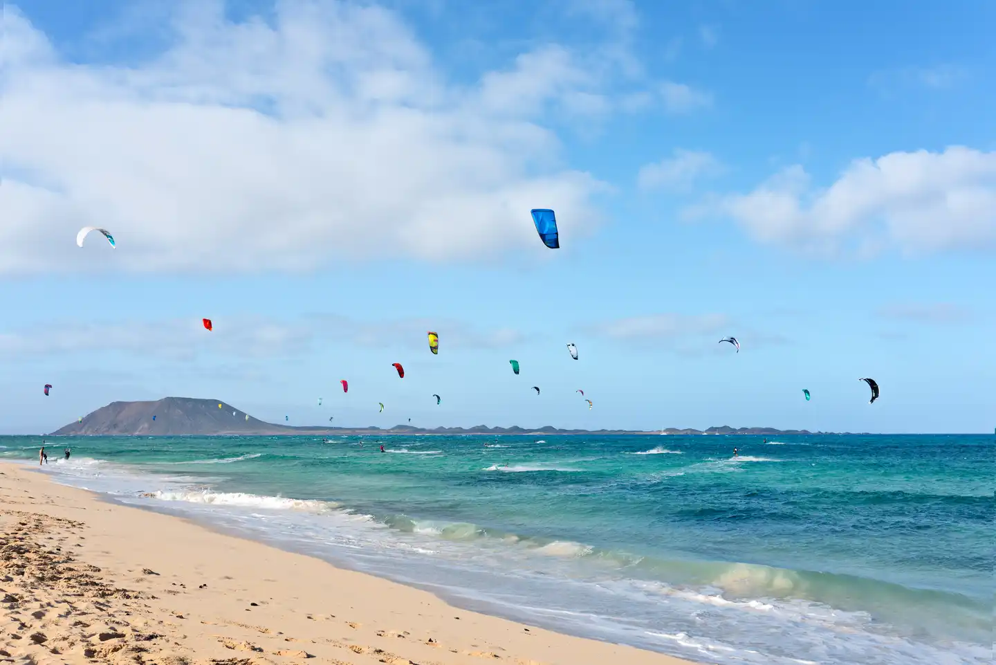 Kitesurfer am Playa de Corralejo auf Fuerteventura mit bunten Kites über dem Atlantik und Blick zur Insel Lobos