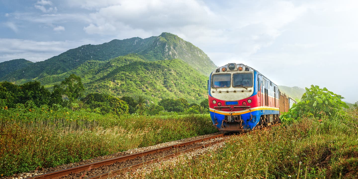 Blau-rot schlängelt sich die Lokomotive durch Thailands Landschaft
