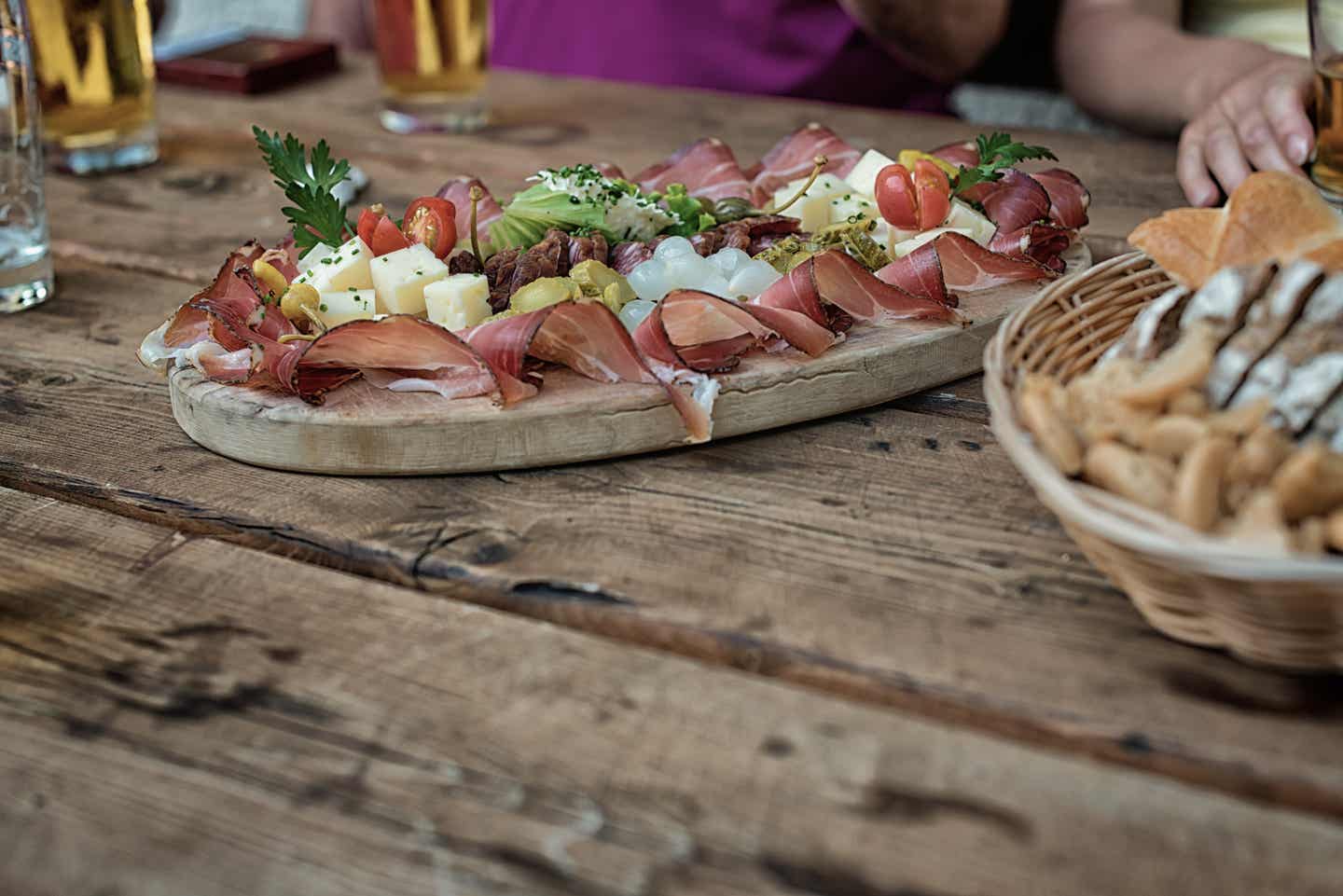 Meran Urlaub mit DERTOUR. Traditionelle Brotzeit-Platte auf dem urigen Tisch einer Berghütte