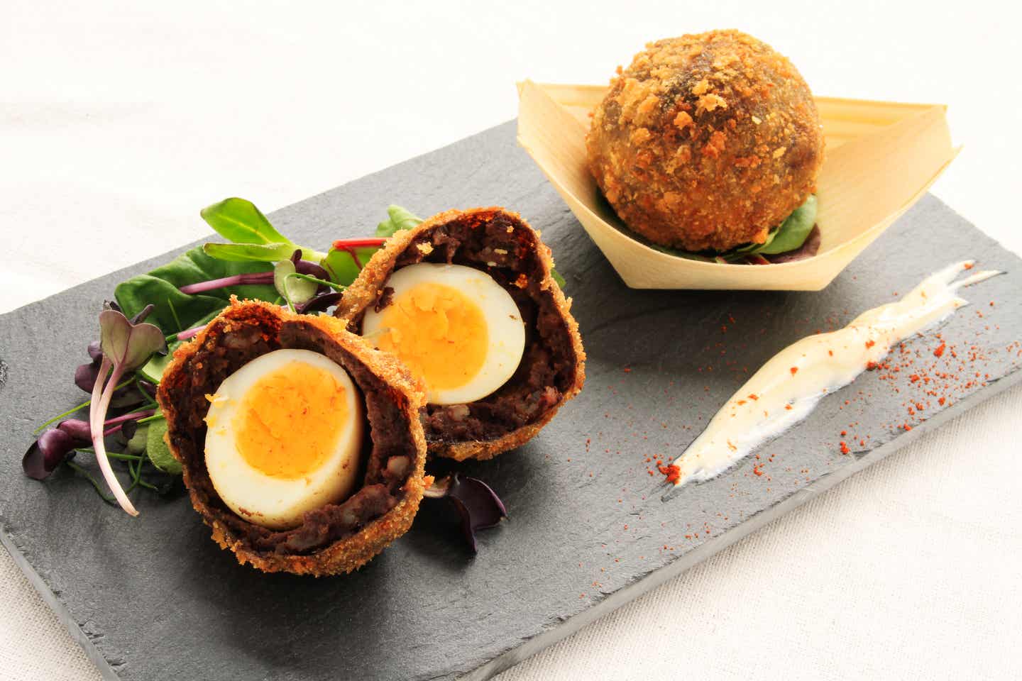 Geschmackserlebnis: Scotch Manchester Ei in Black Pudding, gebreadcrumbed Gekochtes Ei umhüllt von britischem Black Pudding und Breadcrumps, eines aufgeschnitten und eines ganz