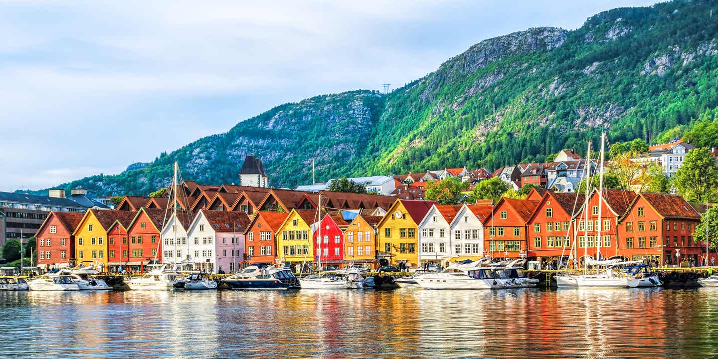 Historische Speicherhäuser in Bryggen am Hafen von Bergen, Norwegen – UNESCO-Welterbe vor grüner Bergkulisse